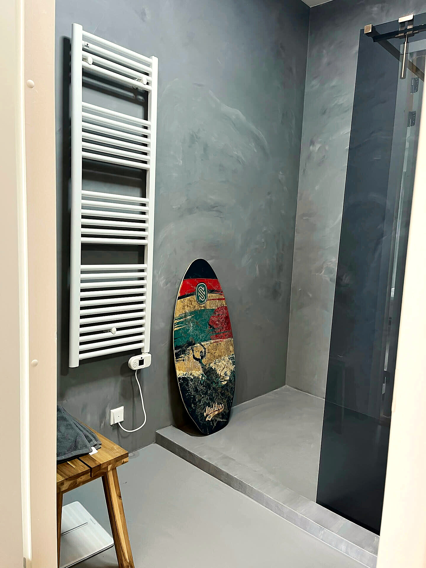 Bathroom with a walk-in shower and a surfboard in the corner