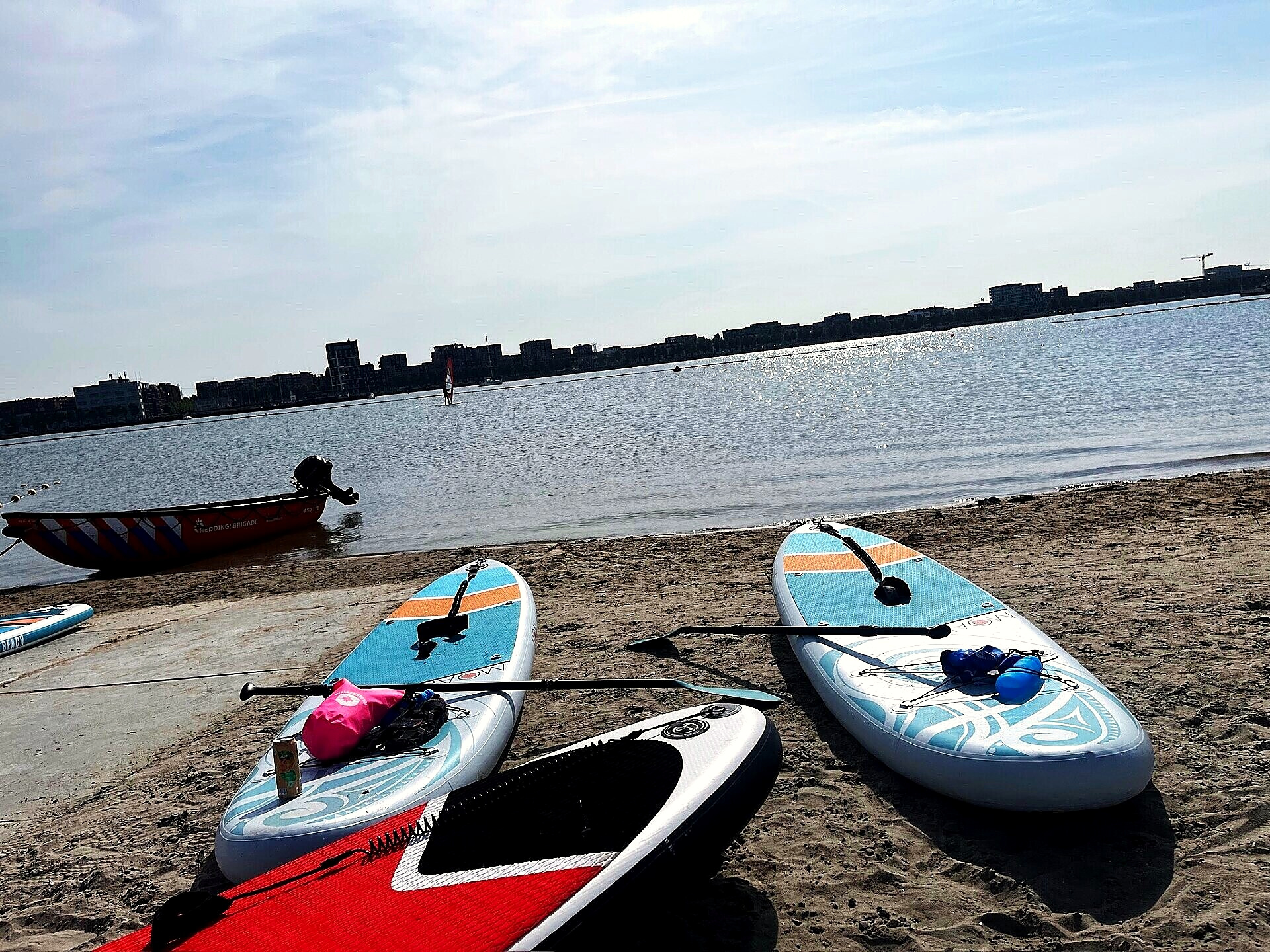 Paddleboards on the sand with the city skyline across the water