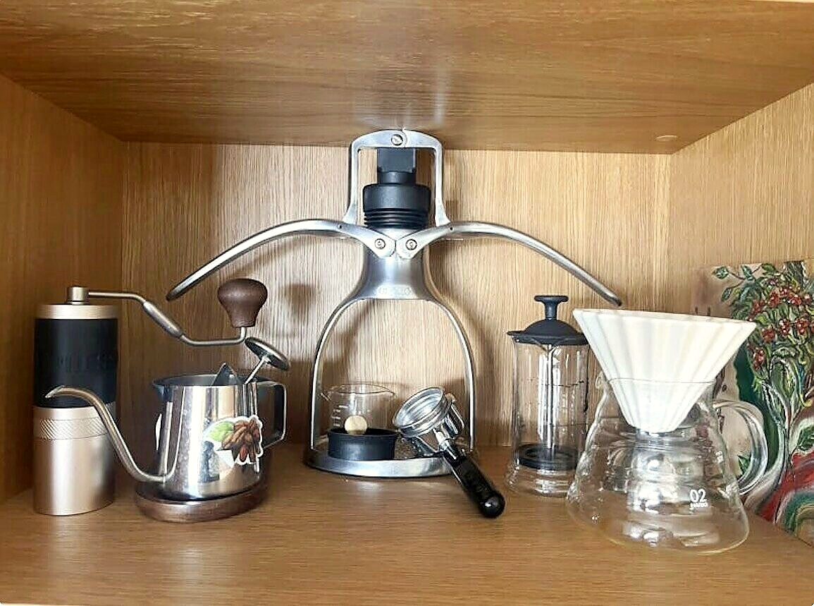 Shelf with an espresso press, grinder, kettle, glassware and a small painting by Nata Orlo