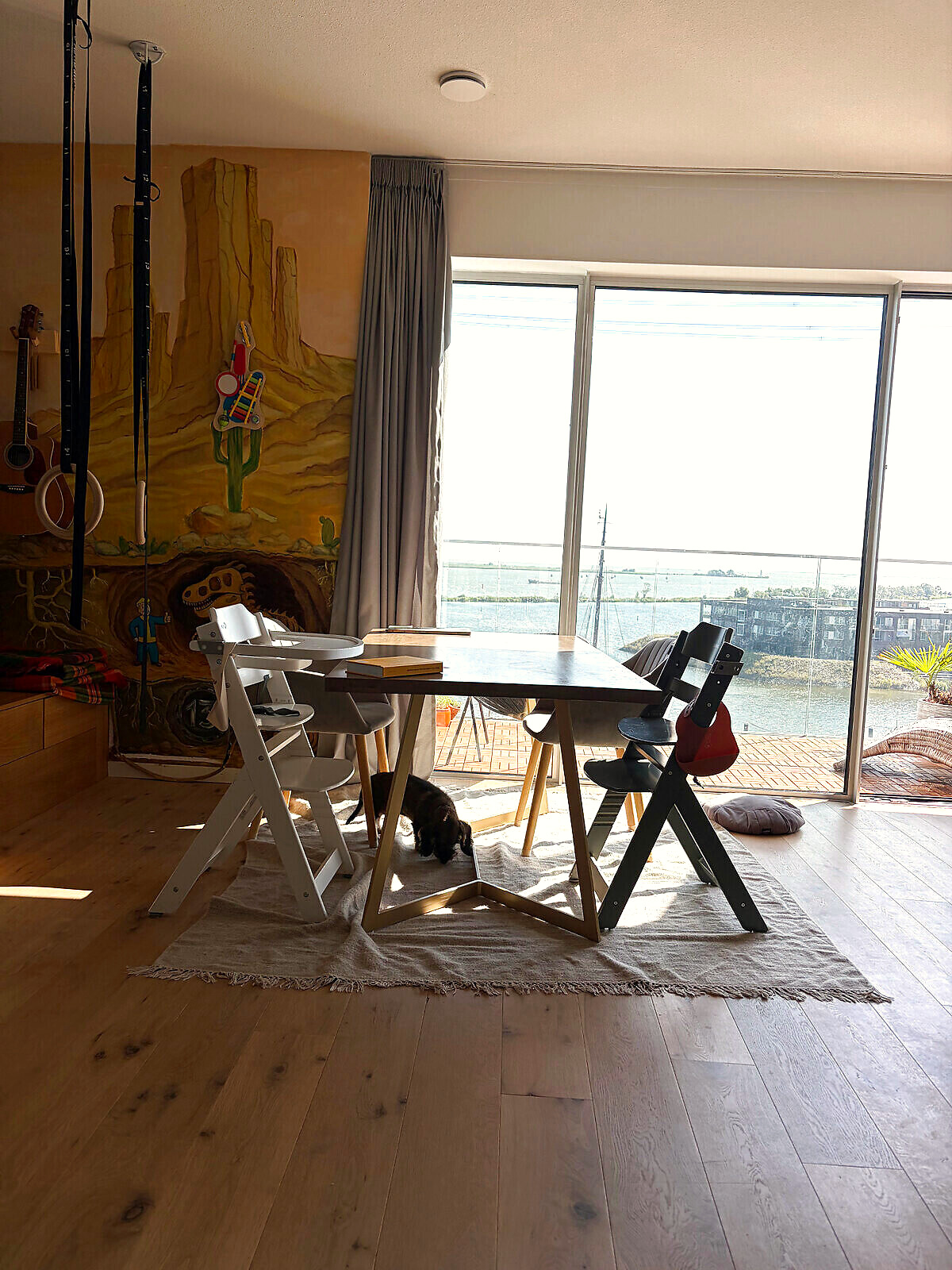 Dining table beside the hand-painted mural with a wide view over the water