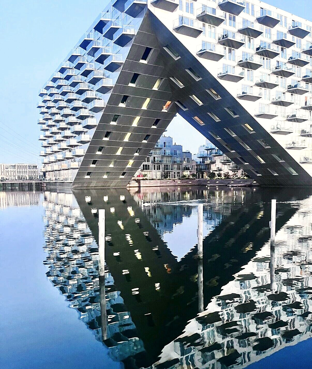The building's cantilevered arch mirrored in still water