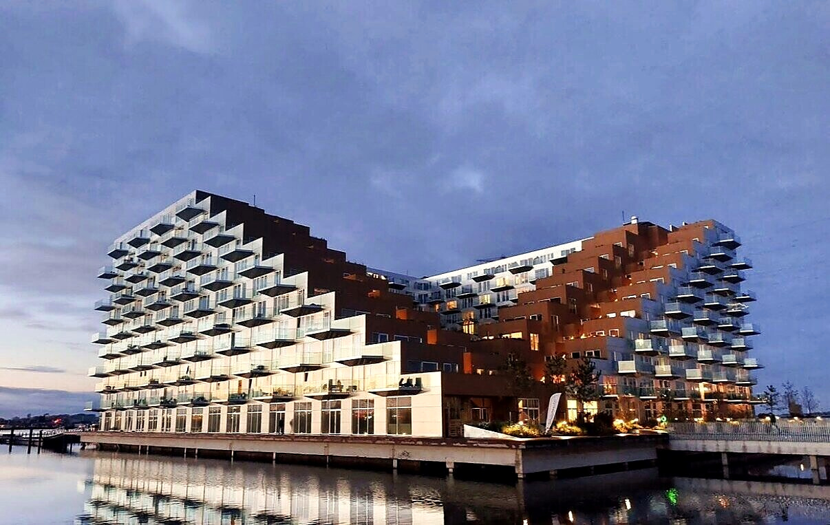 The stepped facade of the building at dusk seen from across the water