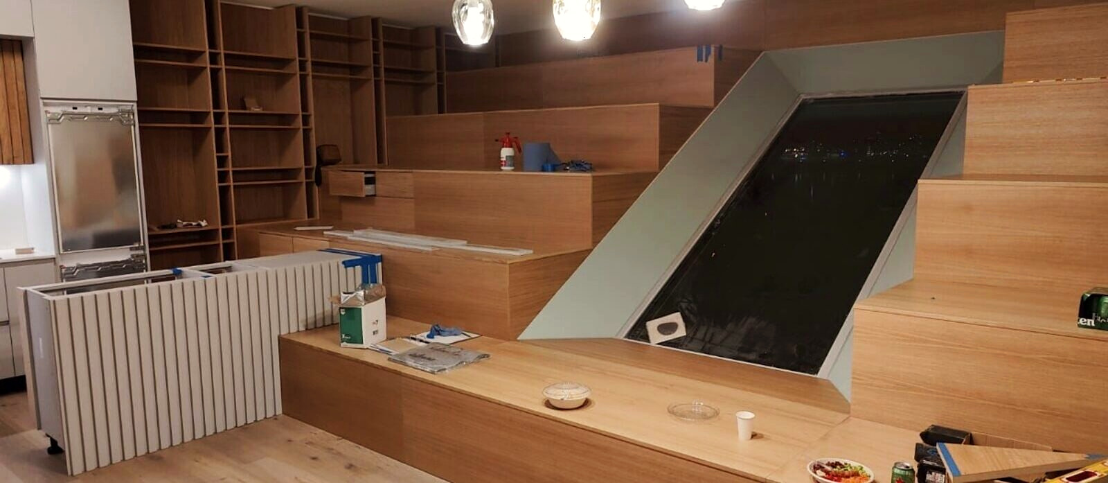 The oak seating wall and kitchen under construction at night