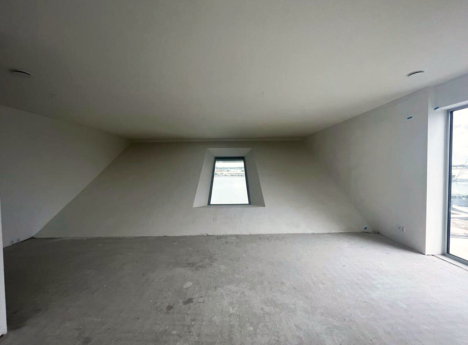 The freshly plastered empty apartment with a slanted window over the water