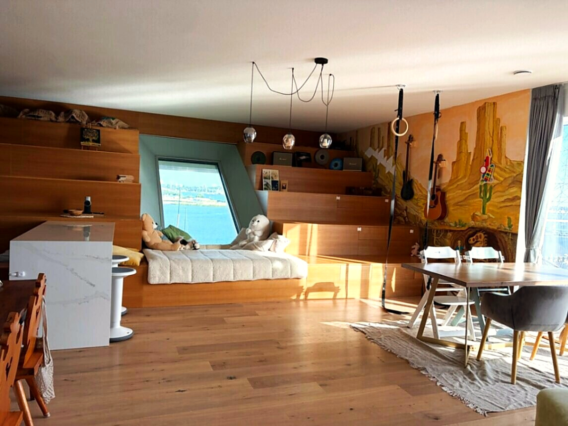 Wide timber living room with a window daybed, hand-painted desert mural and dining table