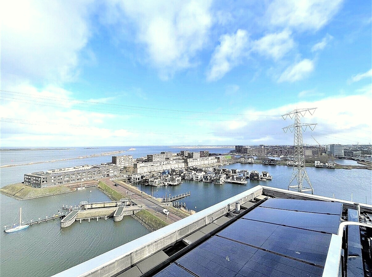 Rooftop view over the water, solar panels and the city beyond